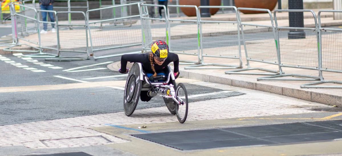 A dedicated athlete competes in a marathon using a racing wheelchair on city streets.