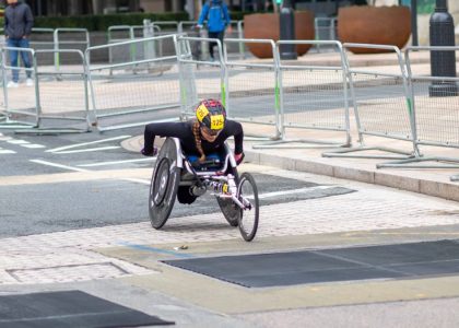 A dedicated athlete competes in a marathon using a racing wheelchair on city streets.