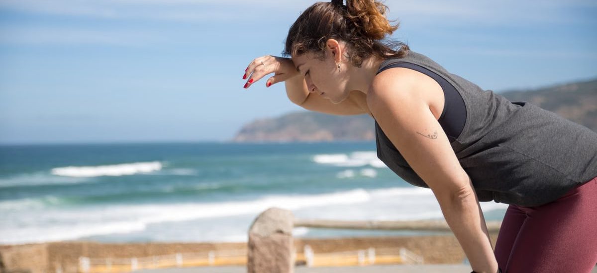 A woman rests after exercise, overlooking the ocean in Portugal's scenic seascape.