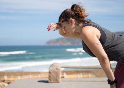 A woman rests after exercise, overlooking the ocean in Portugal's scenic seascape.